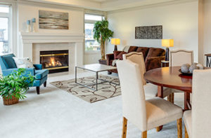 Living room with fireplace, small dining table, and living room furniture has wall-to-wall-white carpet